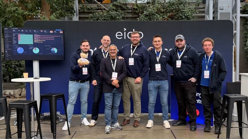 Eight of the Eido team standing in a row in front of the Eido stand at Experts Live Denmark.