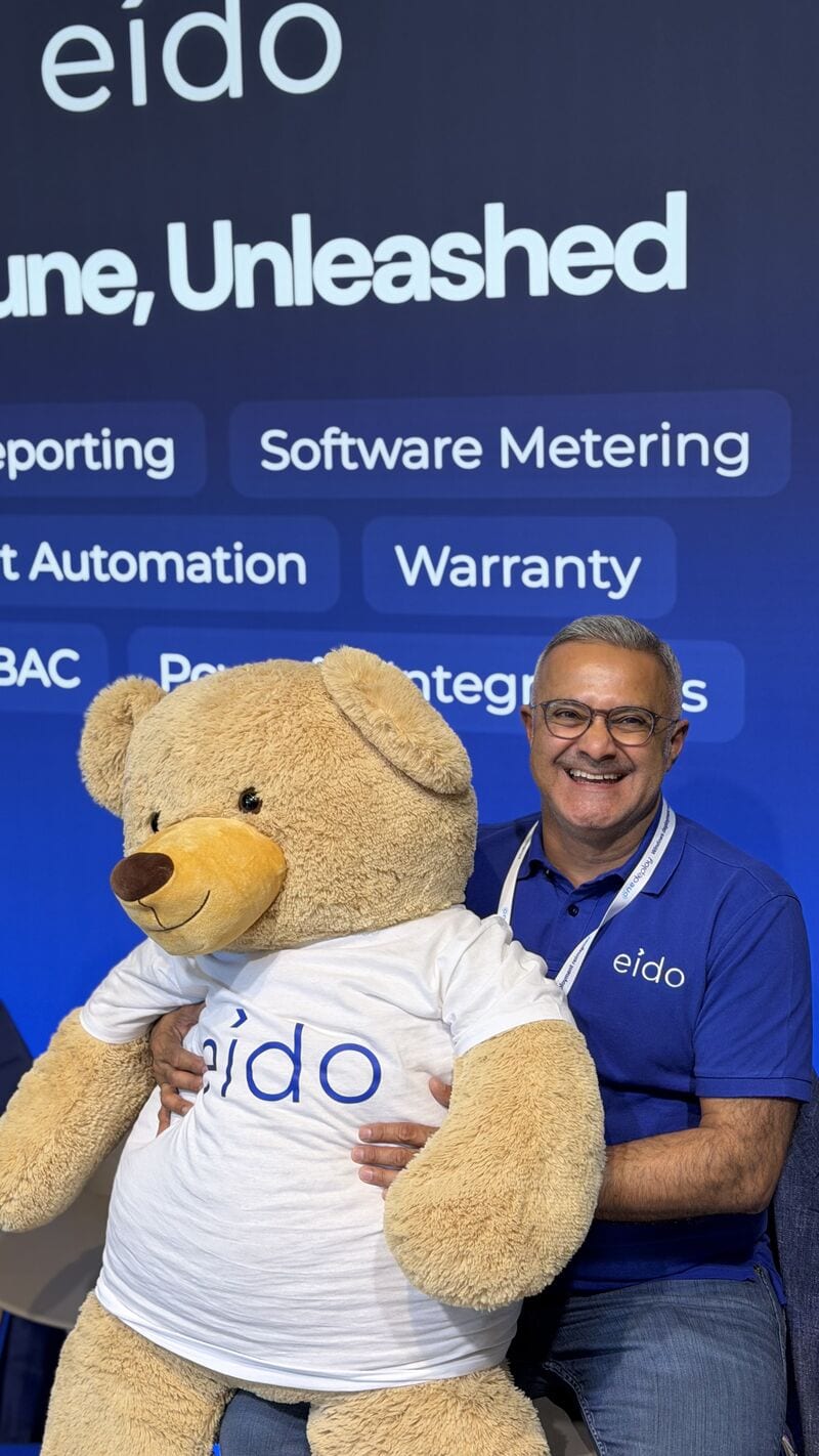 One of the Eido team with an arm around Odie in front of the Eido banner.